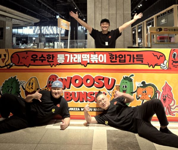 WOOSU BUNSIK 캐릭터 벽화 앞에서 포즈를 취하는 팀원들